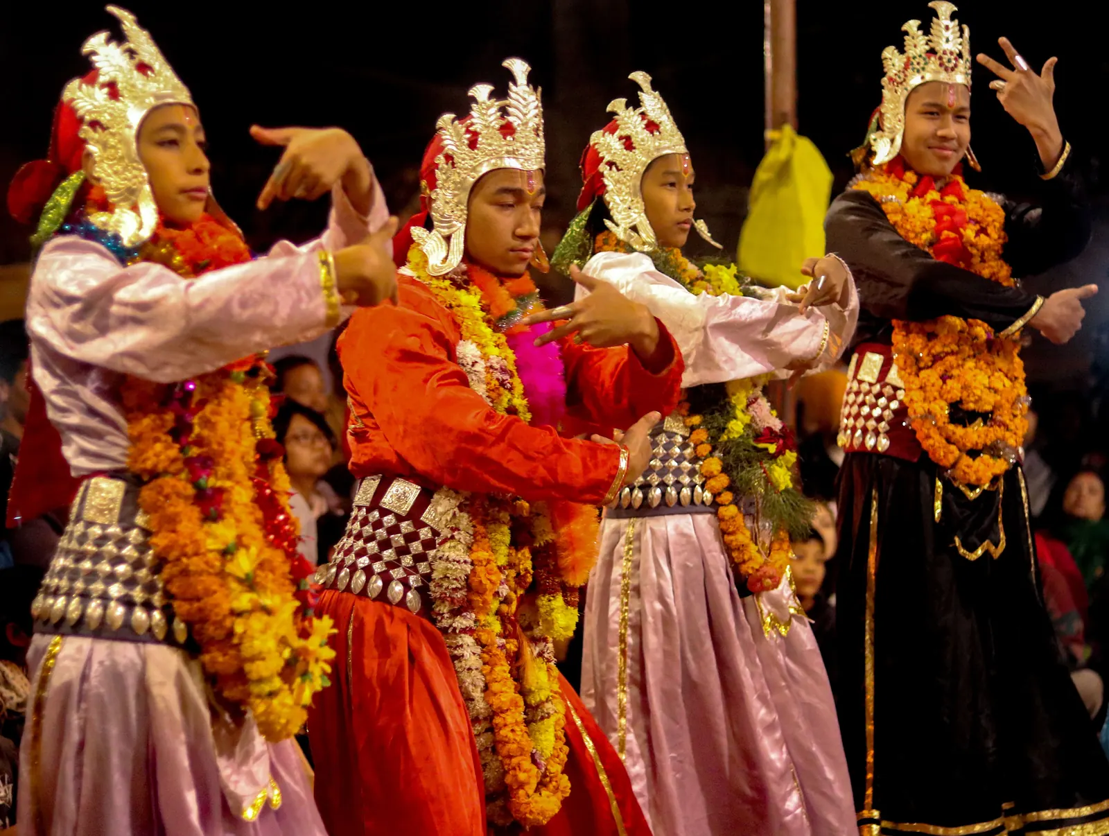 A close group of crowned dancers in bright costumes