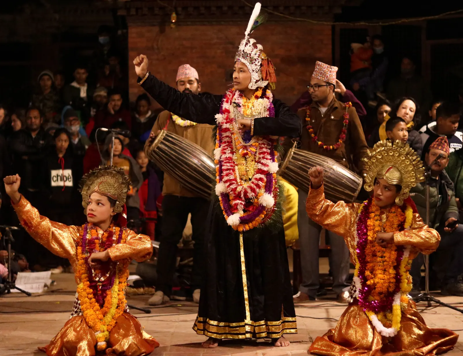Crowned dancers pose low in front of the drummers