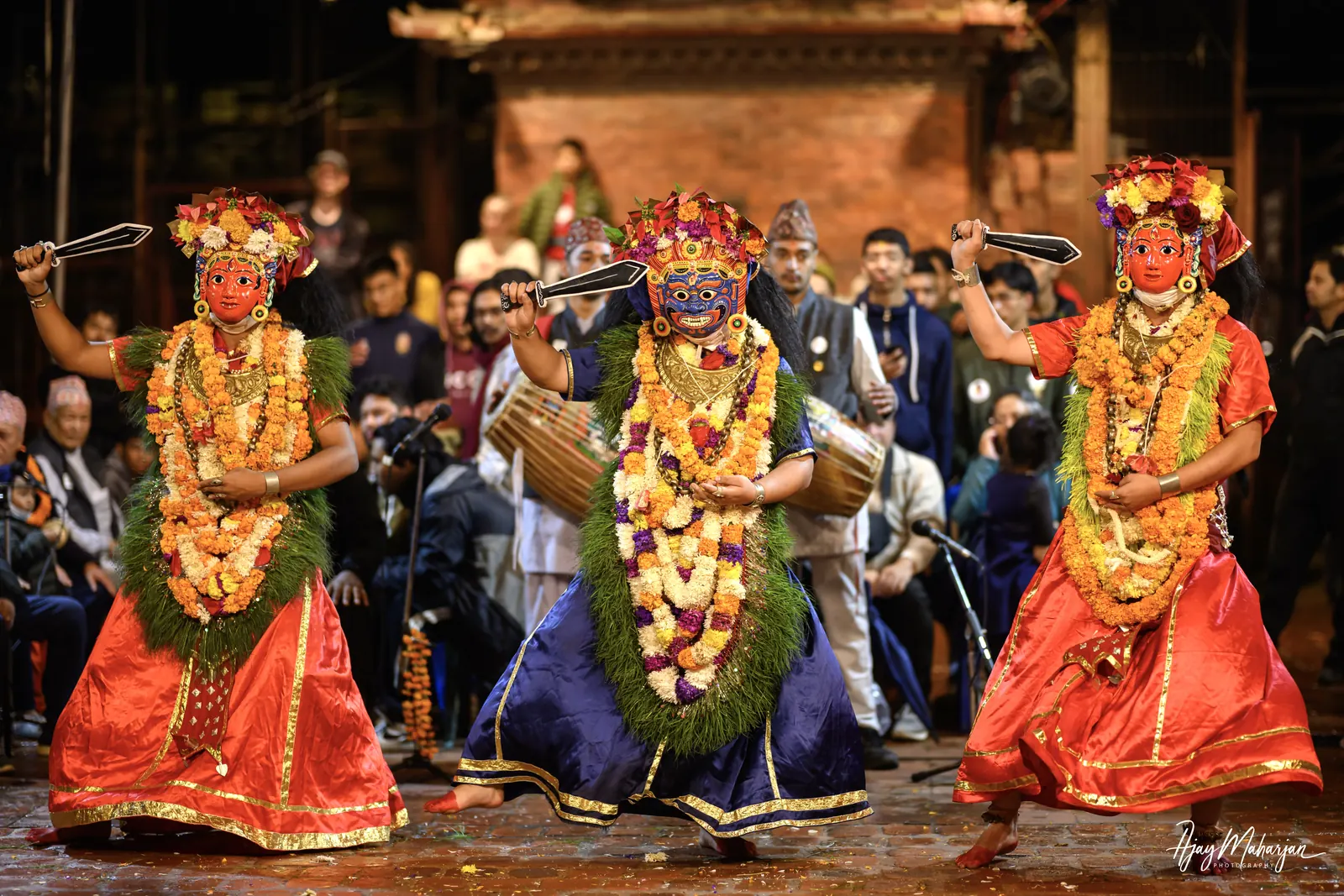 Three masked dancers in garlands perform together