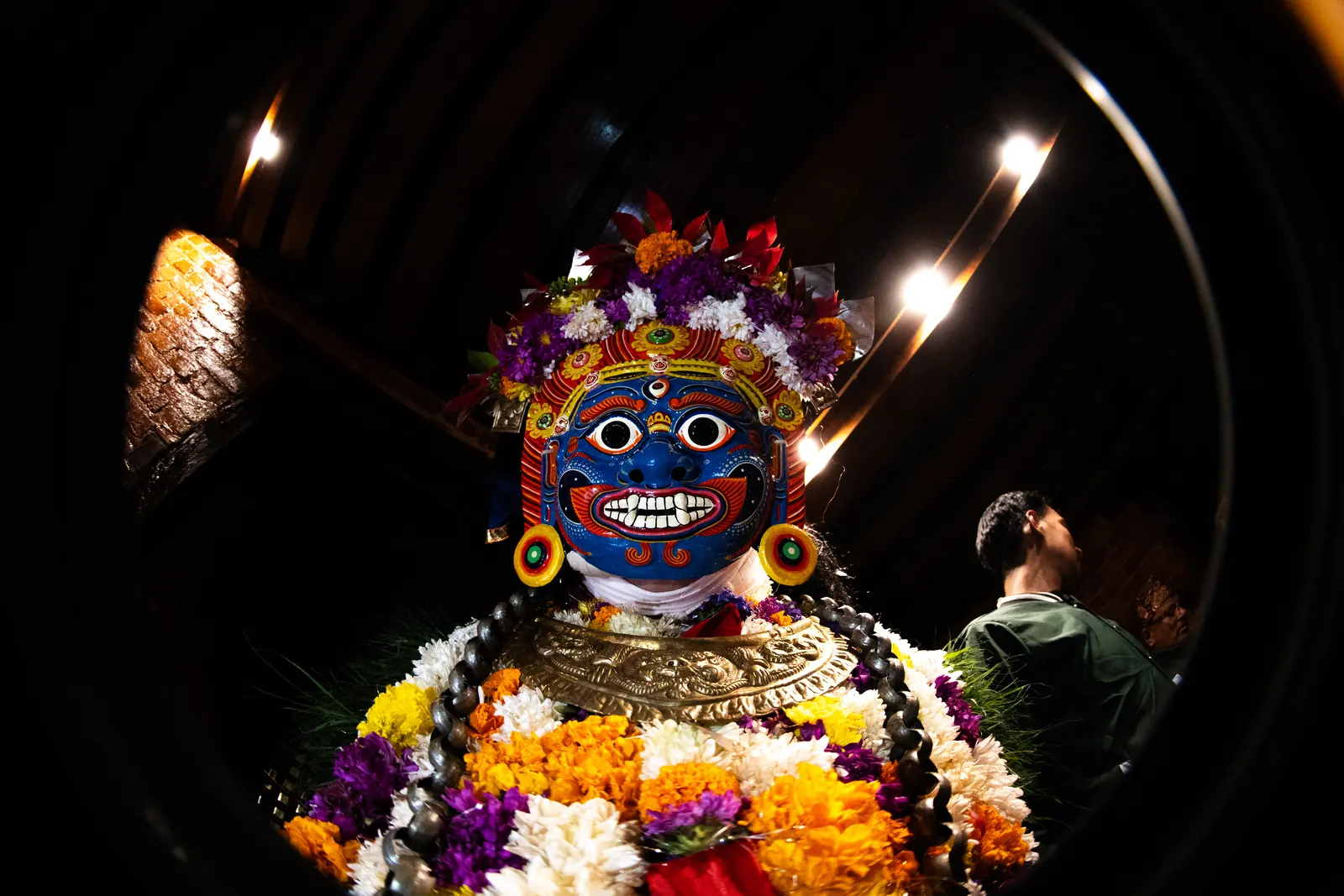 A blue mask framed by lamps in the dark
